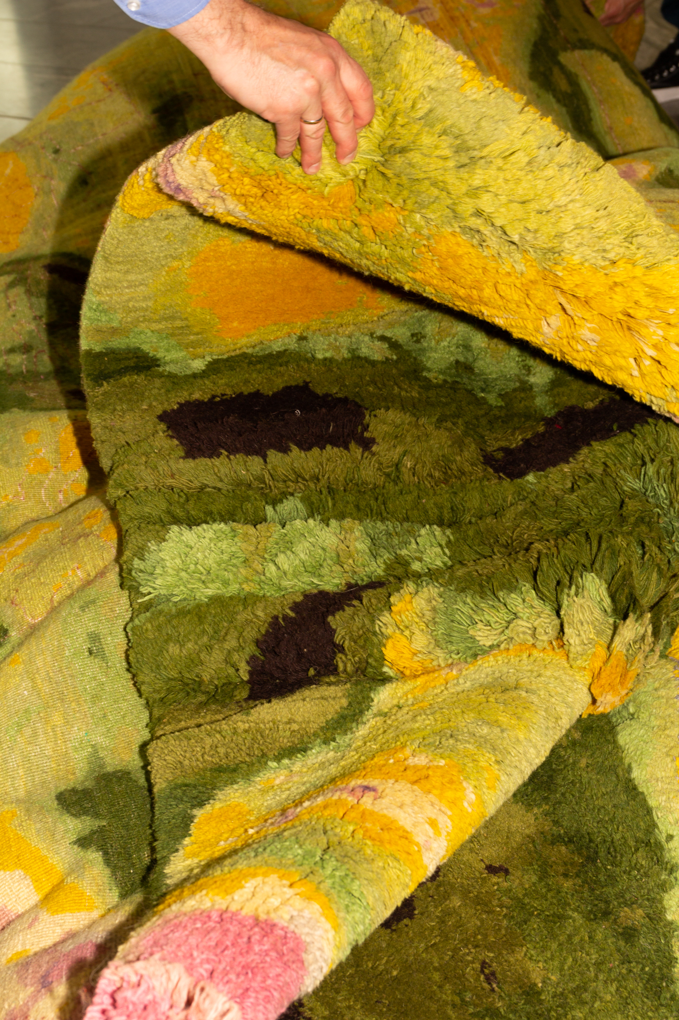 Zusammengefalteter grüner Teppich mit Akzenten in Gelb, Rosa und Dunkelbraun